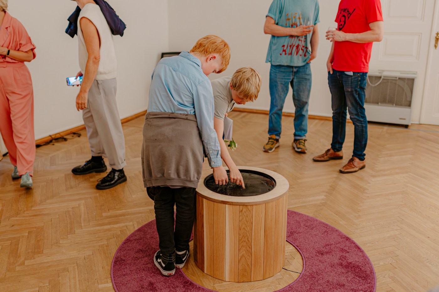 Two children lean over the well and put their hands into the water.