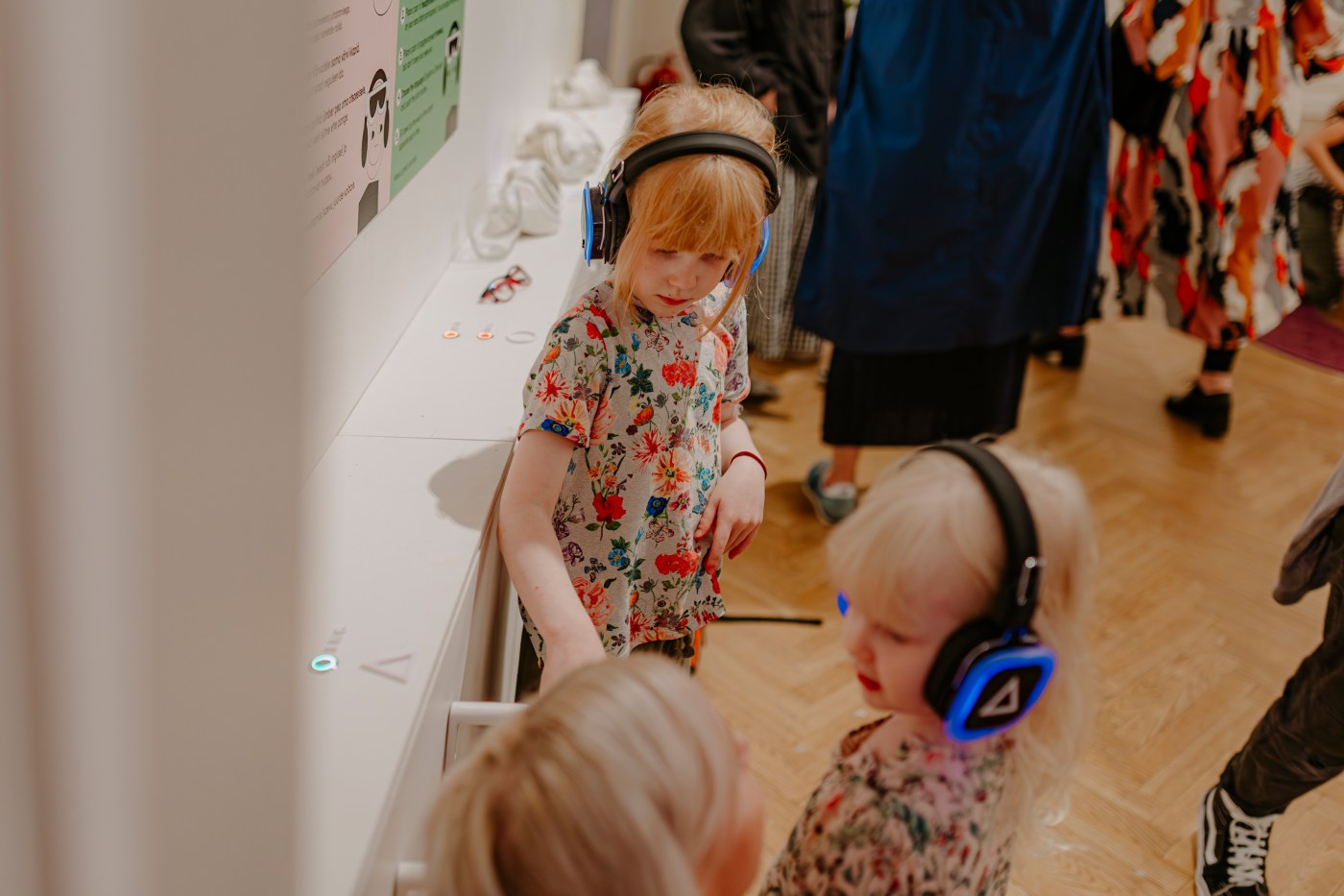 Small children wearing glowing headphones explore the gallery.