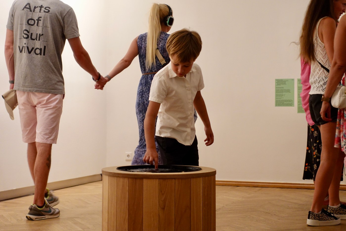 A father and son hold hands while the boy reaches into the well.