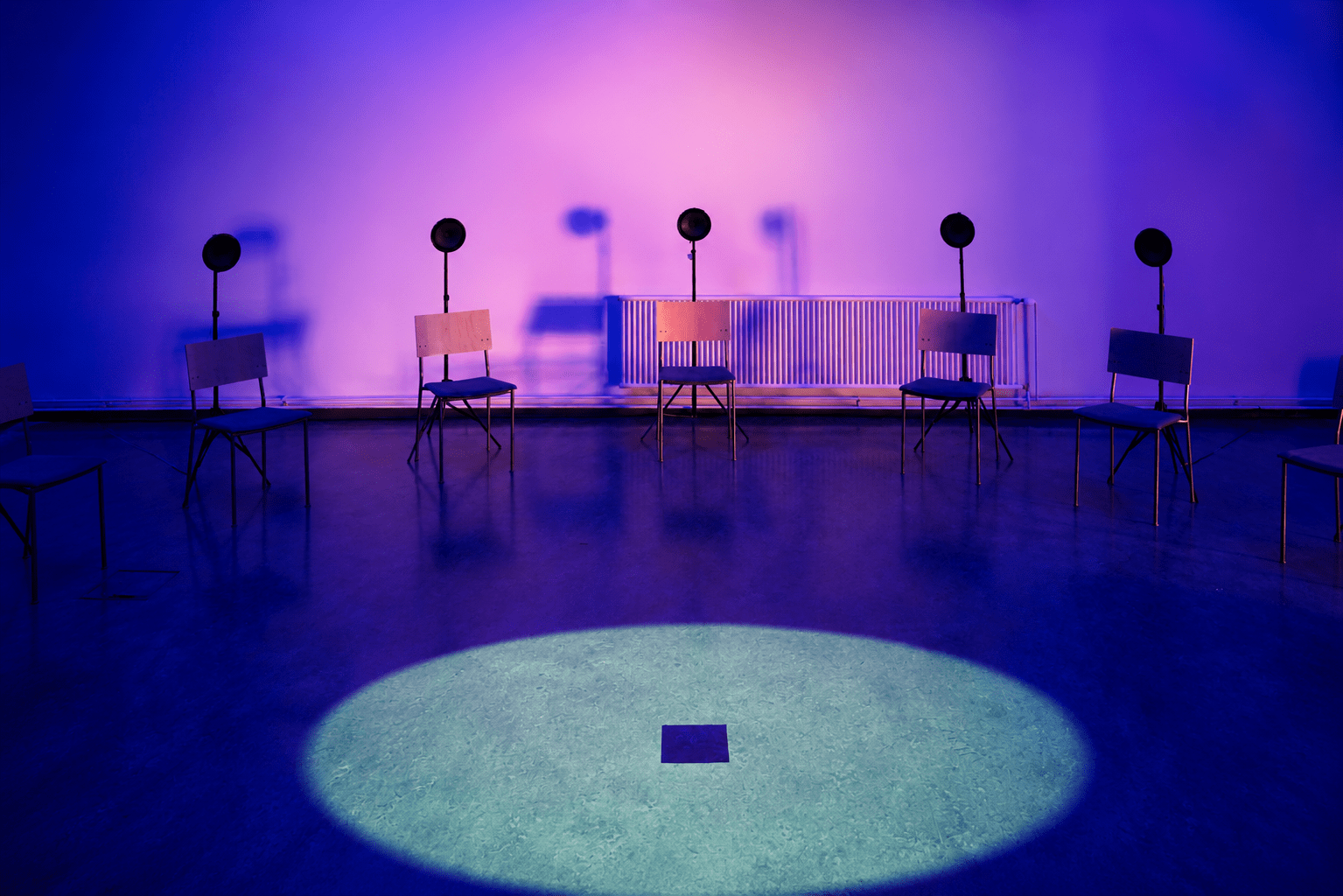 Installation view of INTER SERIES: SALATTU, a 20-channel spatial sound and video installation by Jaakko Autio at Galleria Oiva, Ylivieska. Loudspeakers surround a circular floor projection inside a blue-lit gallery space.