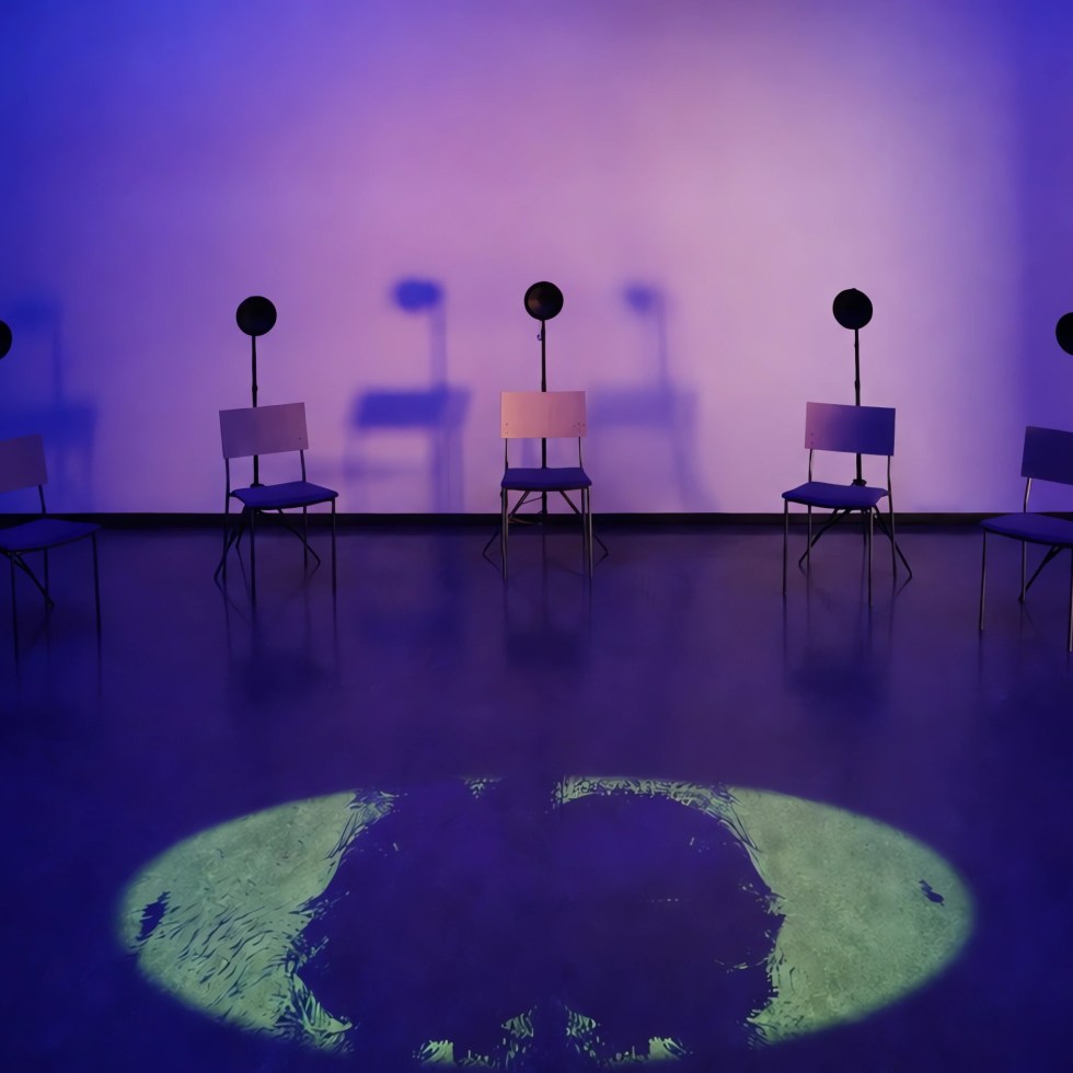 Installation view of INTER SERIES: SALATTU, a 20-channel spatial sound and video installation by Jaakko Autio at Galleria Oiva, Ylivieska. Loudspeakers surround a circular floor projection inside a blue-lit gallery space.